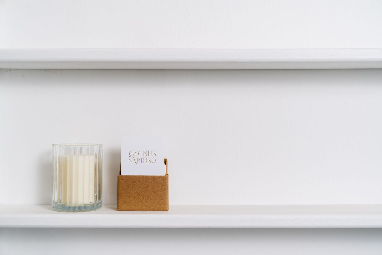 Elegant white candles and wedding decor arranged on a minimalist white shelf.
