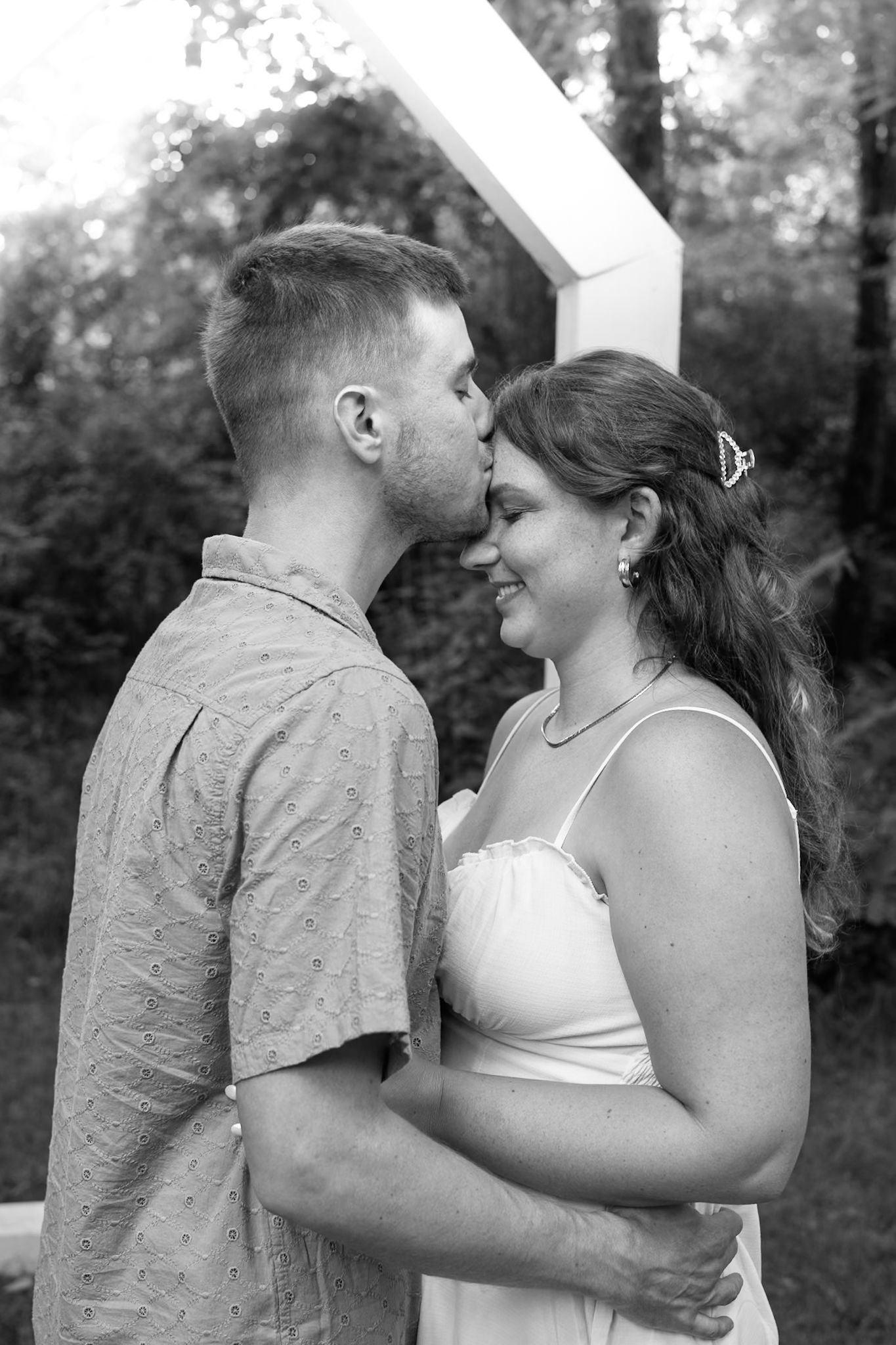 Intimate black and white portraits of a couple sharing romantic moments outdoors.