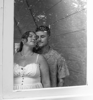 An intimate black and white photo series captures a couple's tender moments by a window.