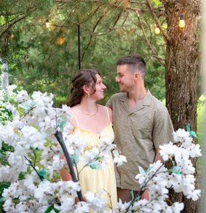 A romantic garden photoshoot with white blossoms and string lights creating a dreamy atmosphere.