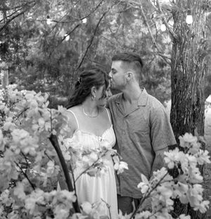 Black and white photo of a couple standing among white blossoms in a garden.