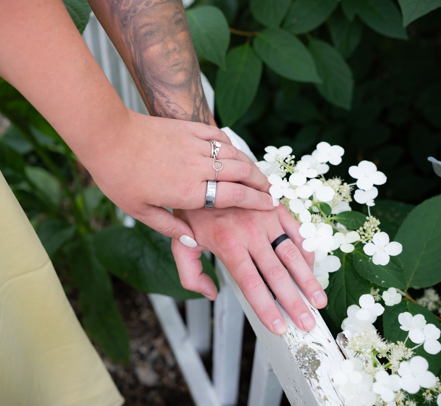 Close-up of hands displaying rings against a backdrop of white flowers.