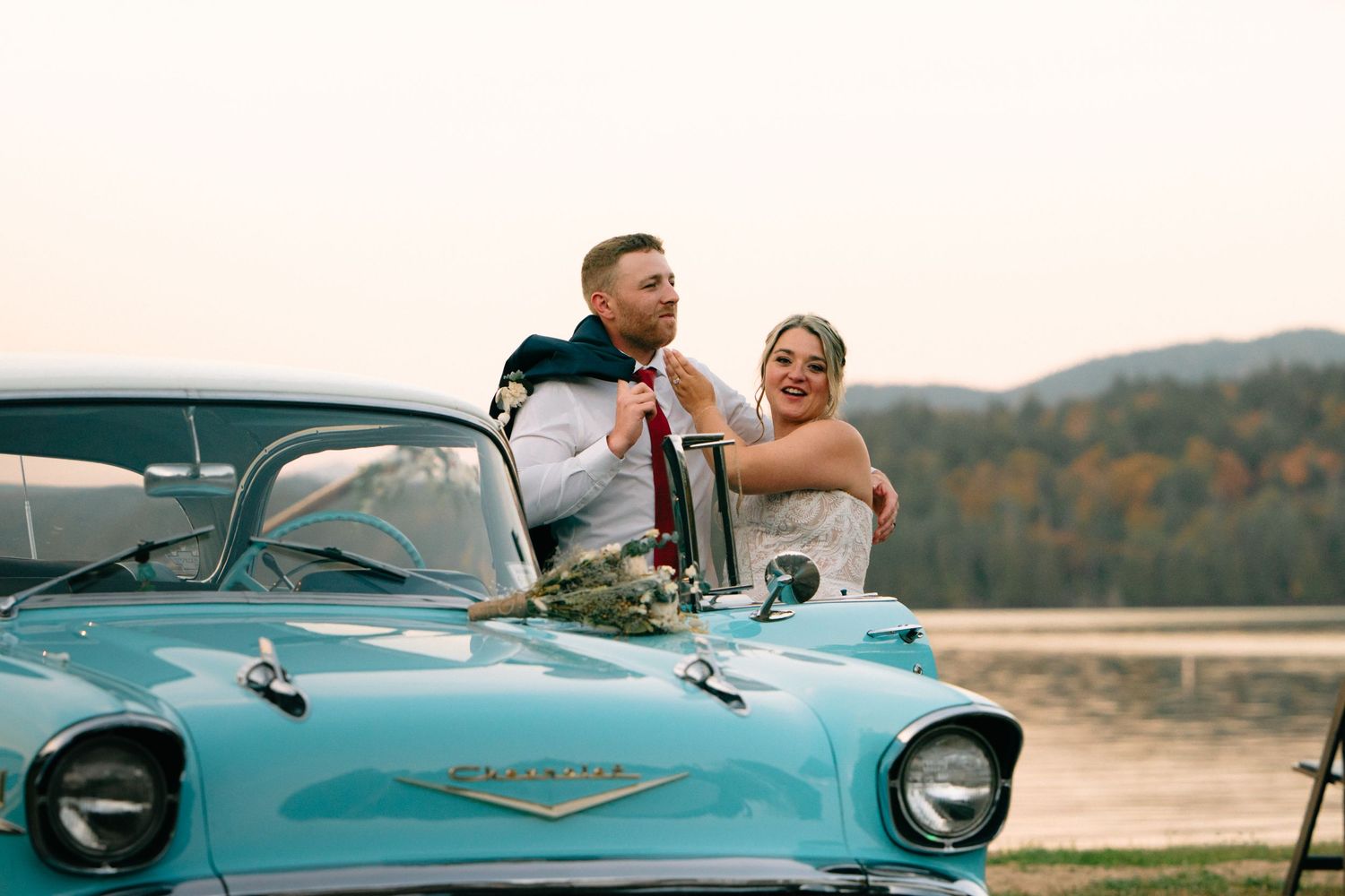 Newlyweds riding in a classic turquoise Chevrolet convertible on their wedding day.