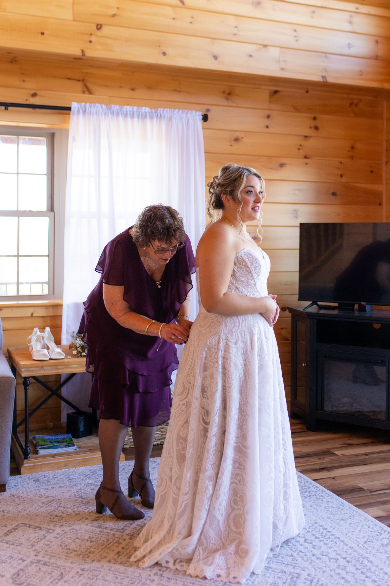 A sequence showing someone helping adjust a white lace wedding dress in a rustic wooden cabin setting.