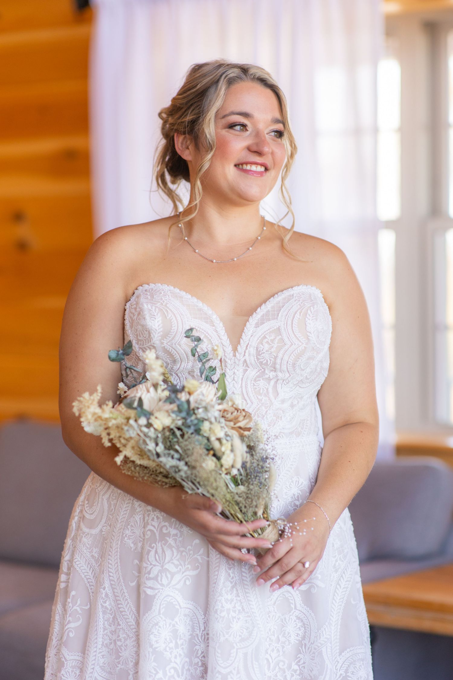 Bride in a white lace wedding dress holding a bouquet with blue and white flowers.