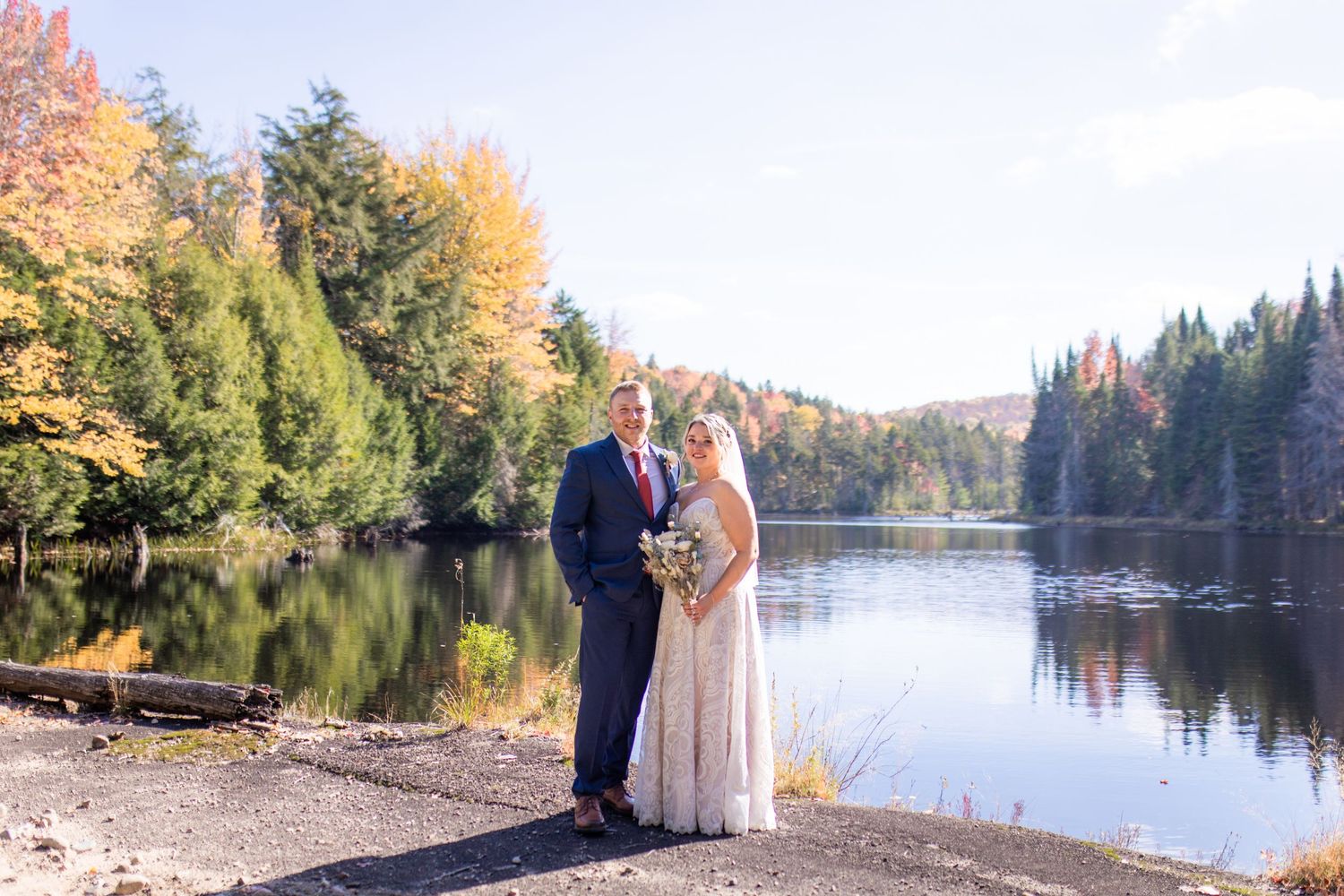 Wedding ceremony by a serene lake surrounded by autumn trees with vibrant fall colors.