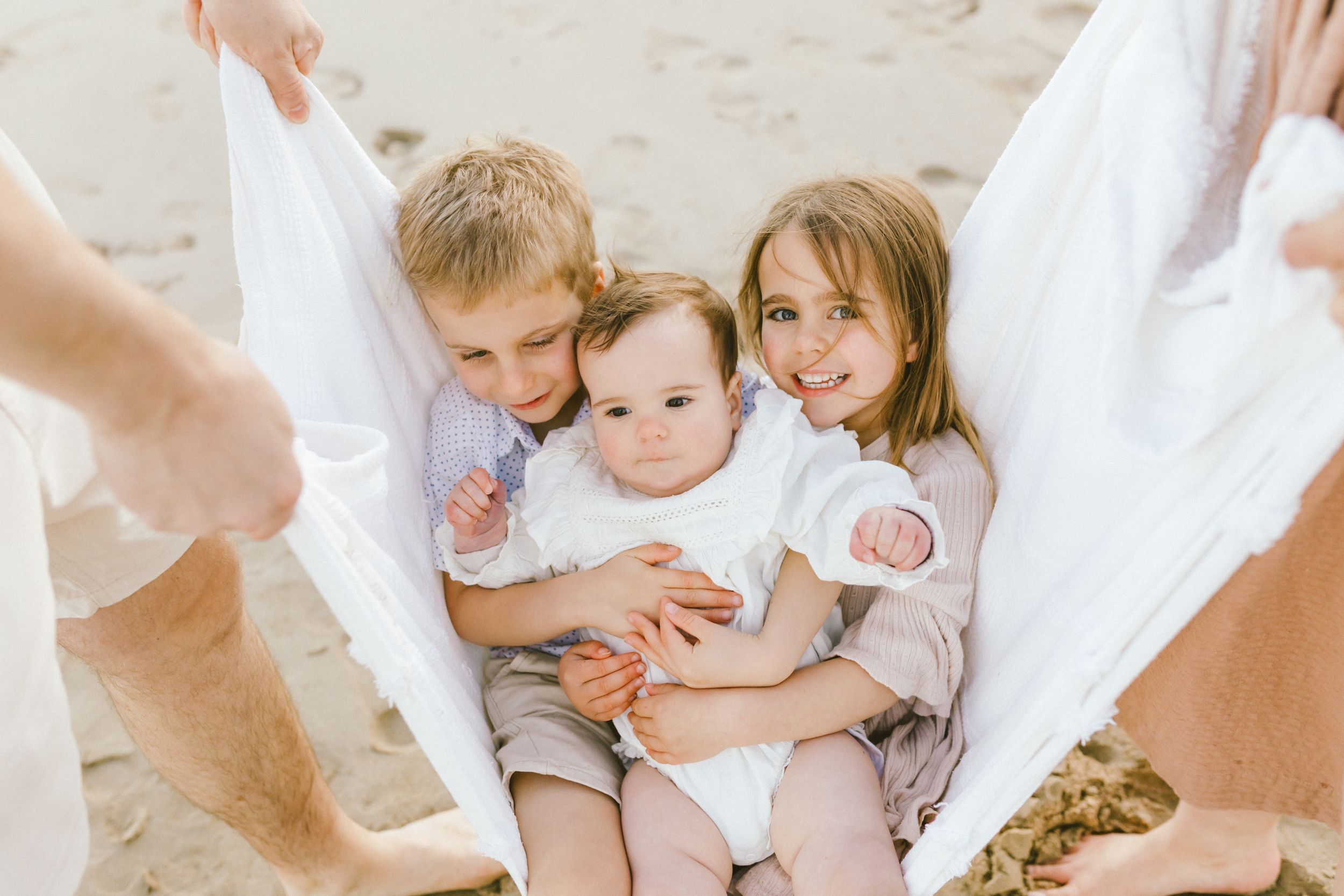 A series of intimate newborn photography moments showing gentle hands holding and cradling babies in soft white settings.