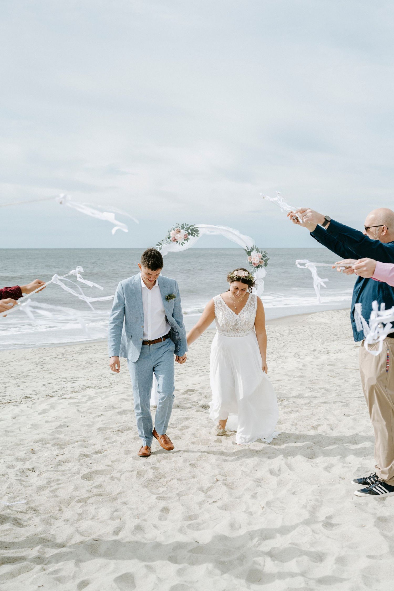 Wedding party creates fun photo moments with streamers on sunny beach.