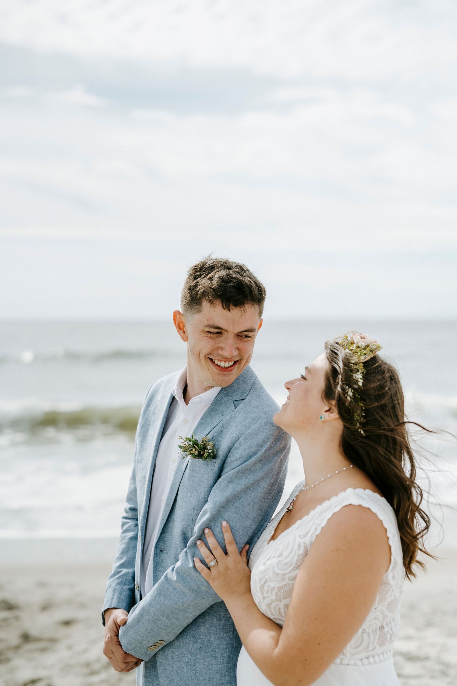 A couple shares a joyful moment together on a beach during their wedding day.