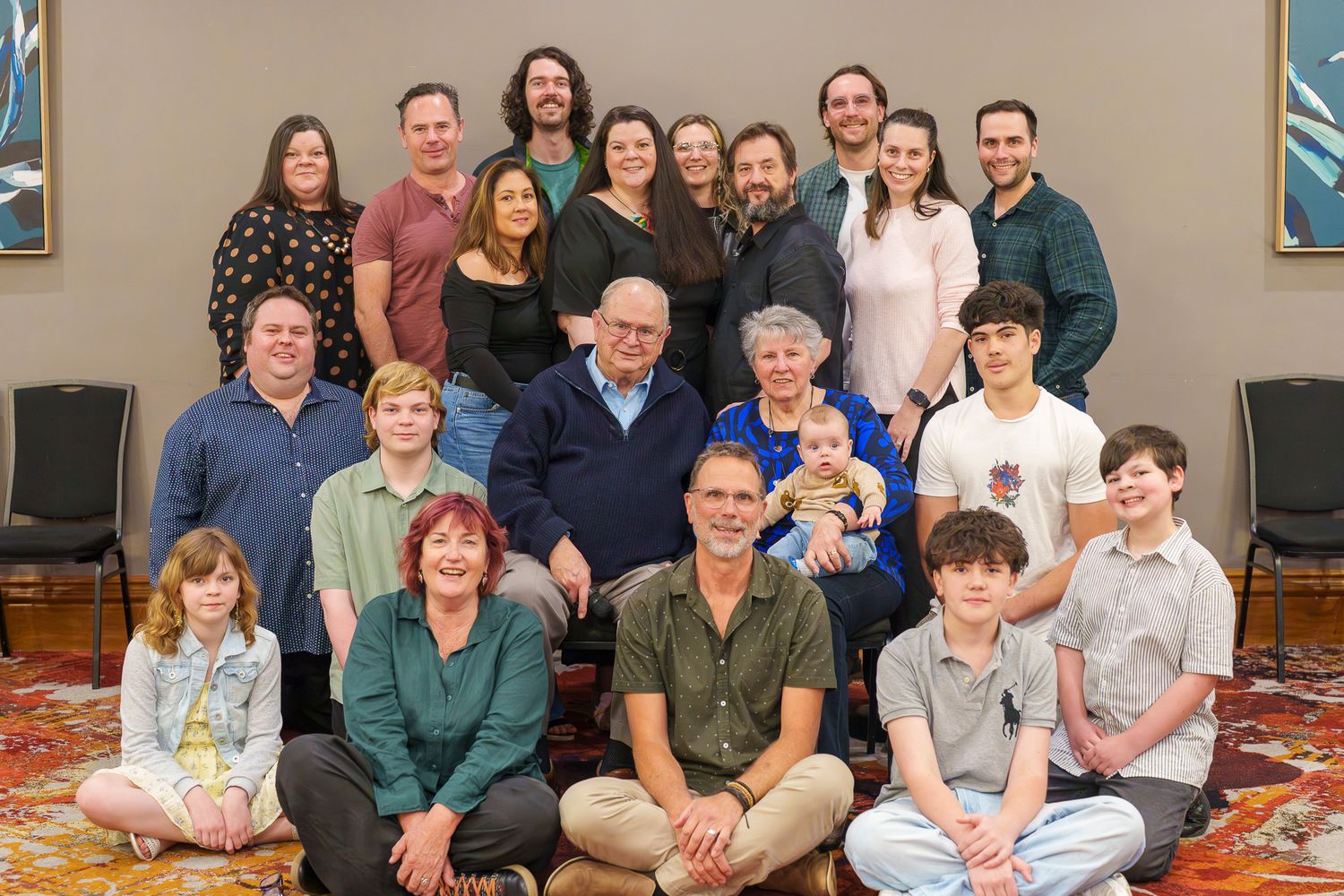 Large multigenerational family group poses together for a formal portrait in a warmly lit room.