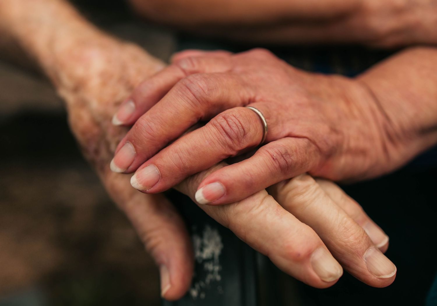 Close-up photo of hands touching and connecting in a gentle, intimate gesture against a dark background.