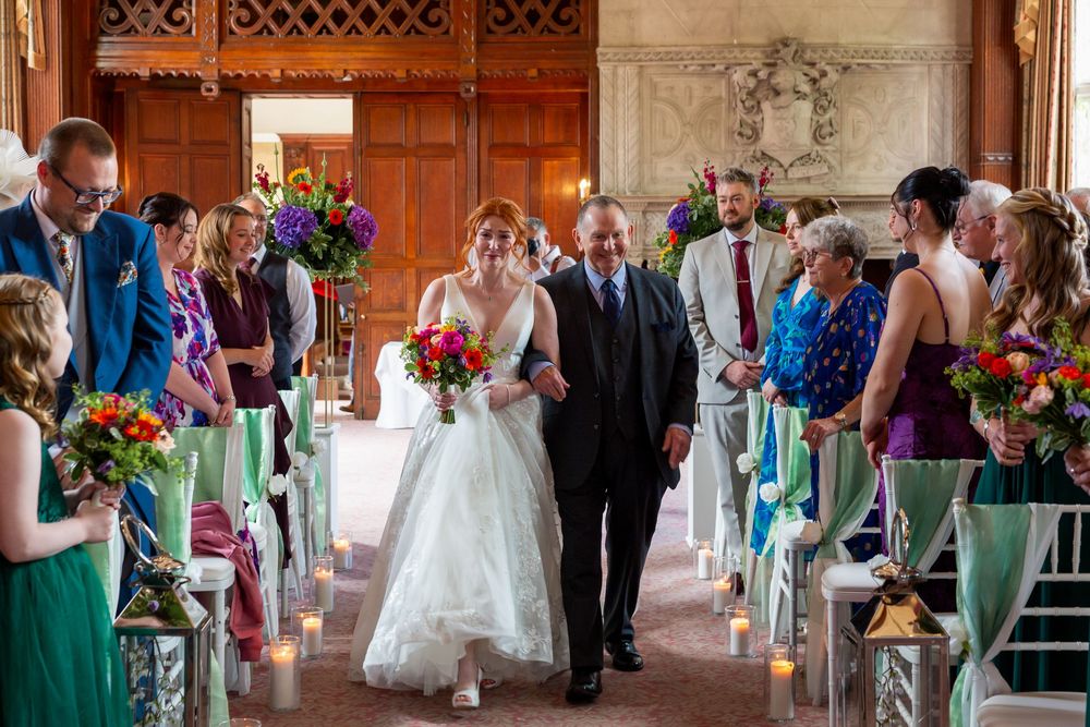Wedding party members in mint green dresses line up to greet the bride and groom during a receiving line at a church.