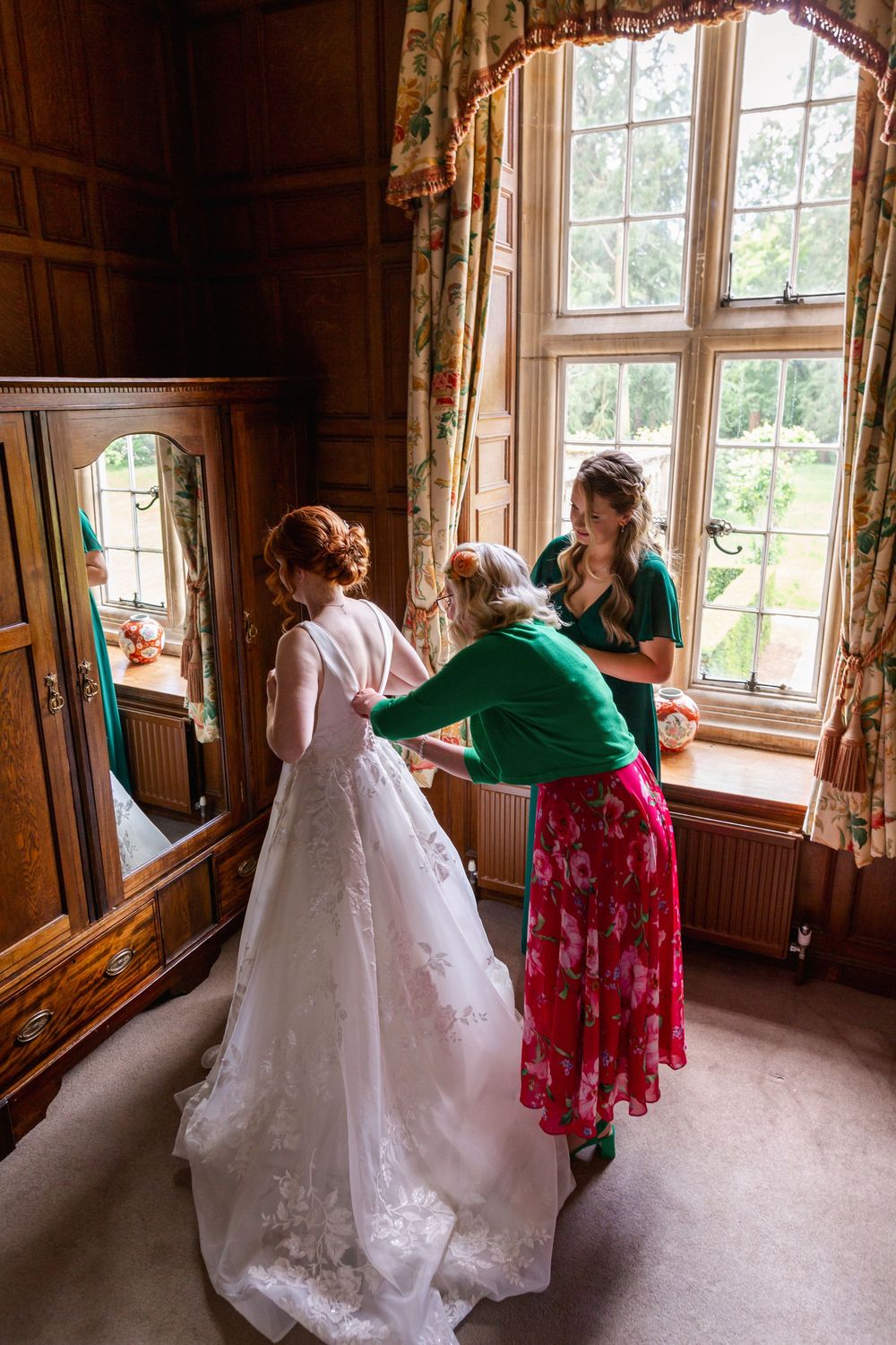 A series of photos showing a white wedding dress being adjusted near a sunlit window in a rustic wooden room.