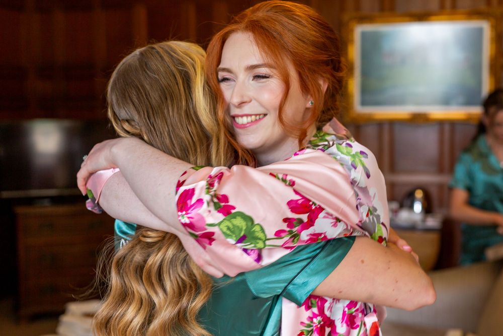 Two people share a warm embrace while wearing floral print clothing in an indoor setting.