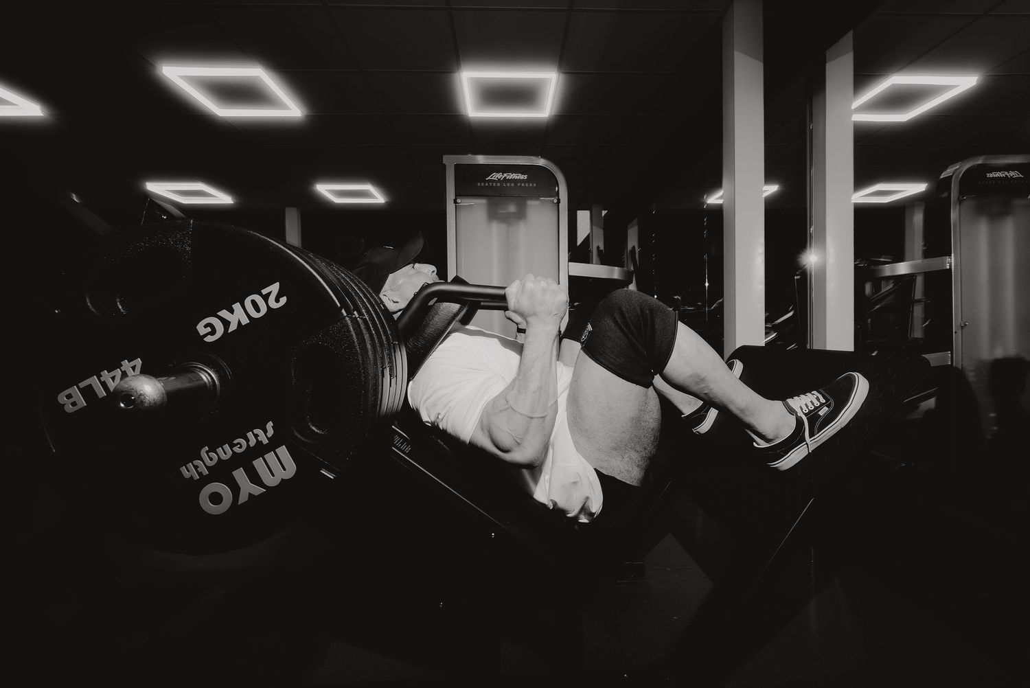 Person performing leg raises on decline bench in black and white gym setting.
