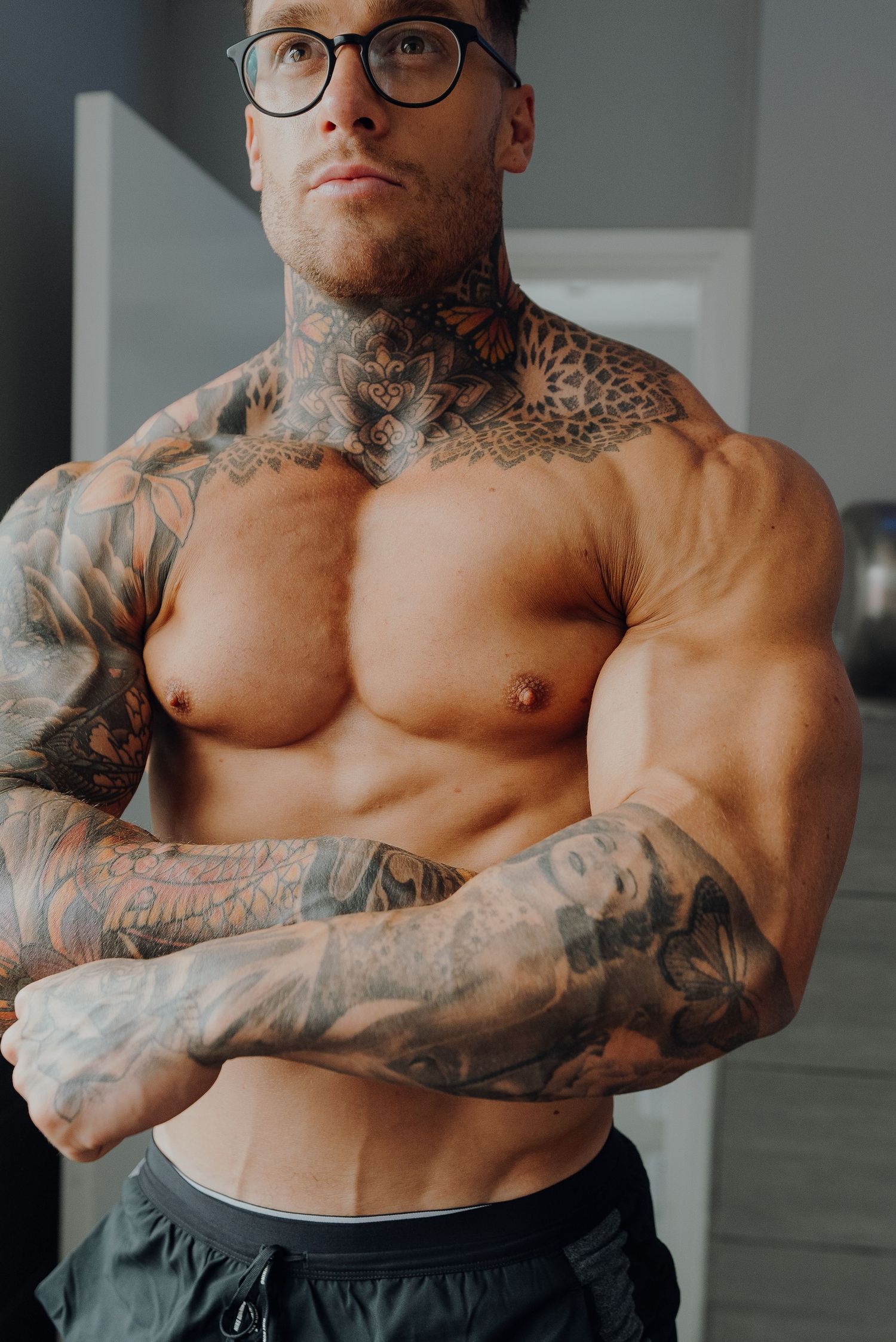 Muscular torso with extensive tattoo artwork covering the arms and chest.