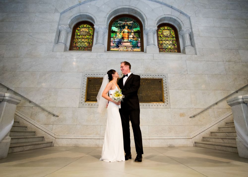 A couple shares a romantic moment during their wedding ceremony in an elegant stone church interior.
