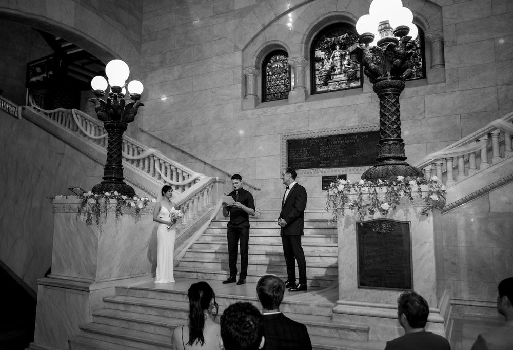Black and white wedding photos show a grand staircase celebration sequence with elegant lighting and architectural details.