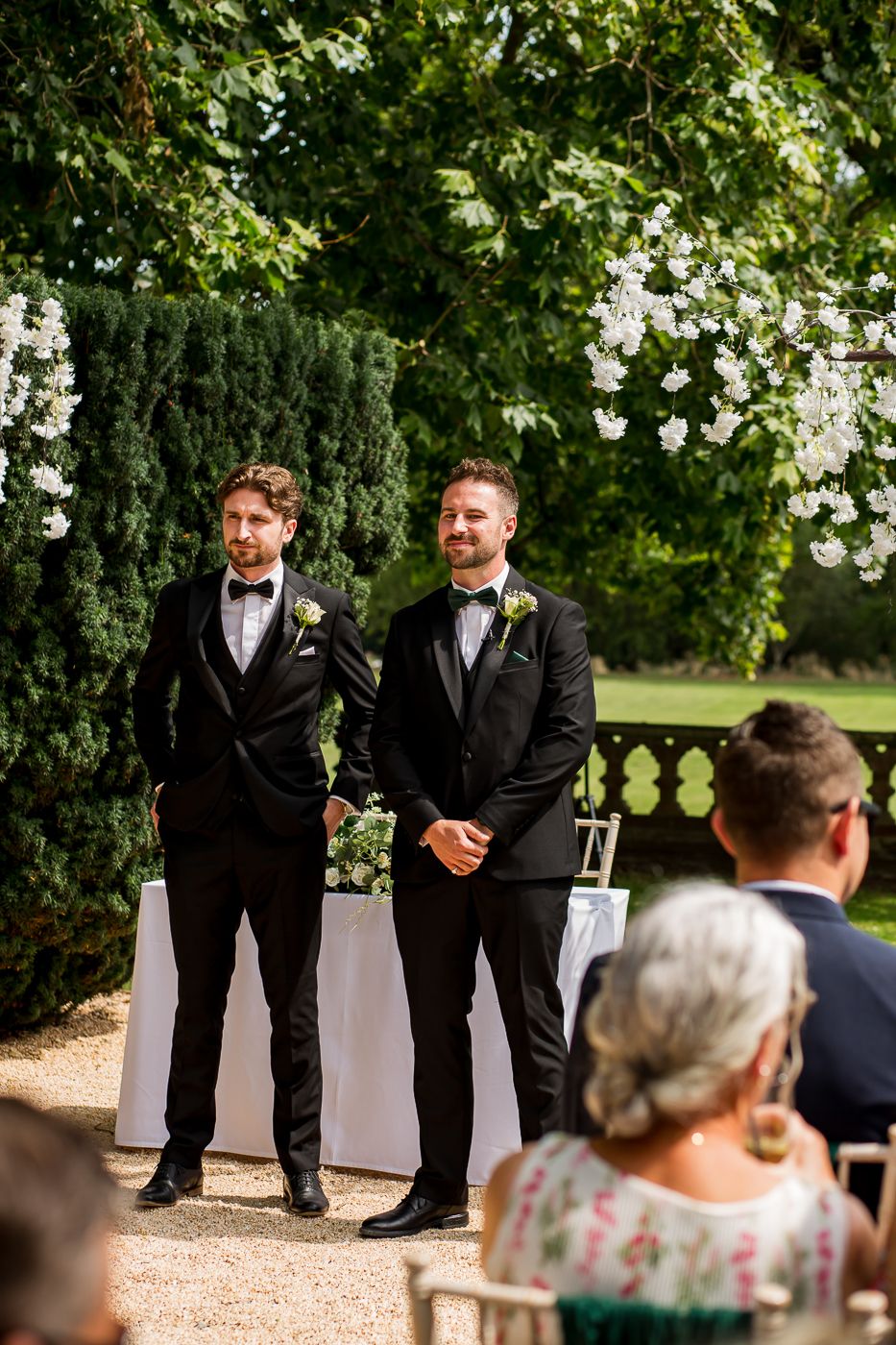 Groomsmen share jokes and laughter during a garden wedding ceremony.