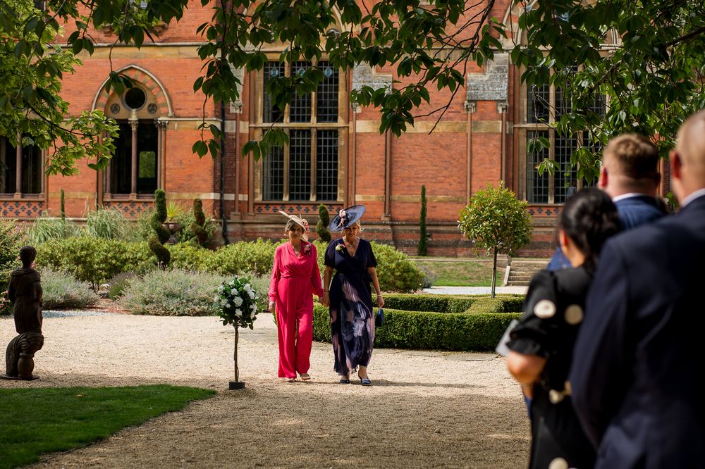 People gather outside a historic red brick building during a wedding event.