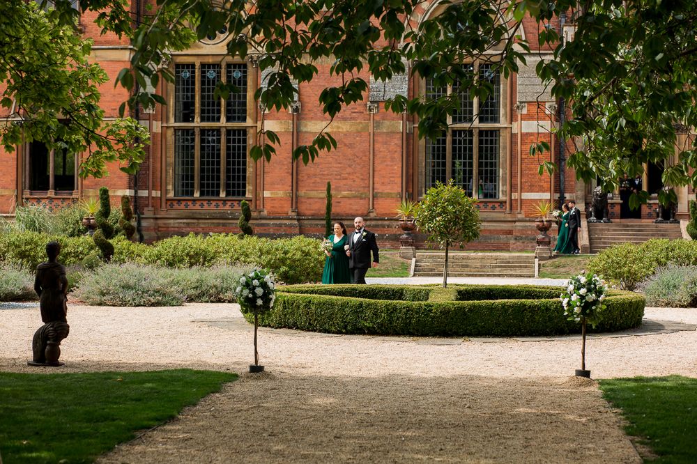 Elegant outdoor ceremony space with formal landscaping and red brick architecture in the background.