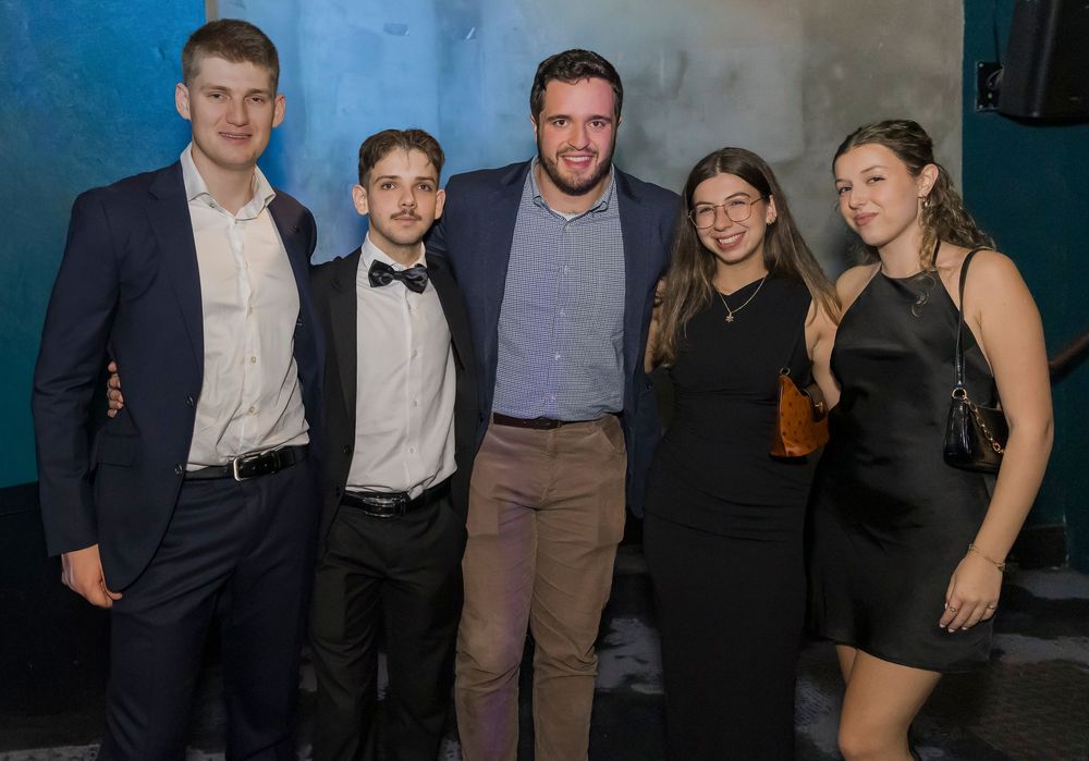 Group of people in formal attire posing together at an evening event.