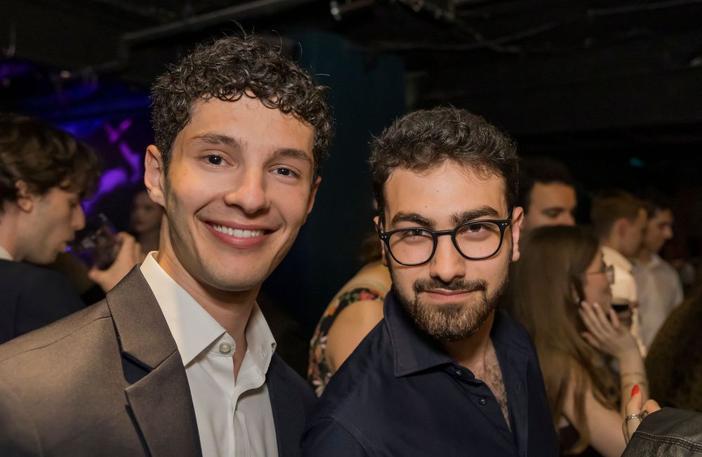 A group of people smile and pose together at what appears to be a formal evening event or celebration.
