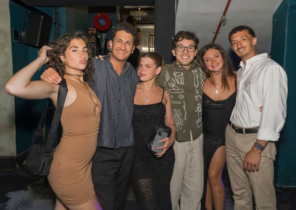 Group of people laughing and having fun at a dimly lit party or social gathering.