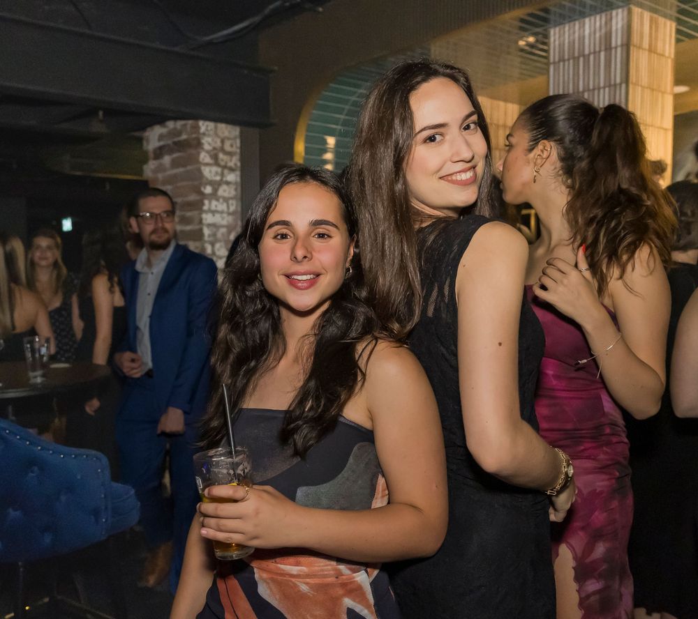 People enjoying a lively social gathering at an indoor venue with dim lighting and festive atmosphere.