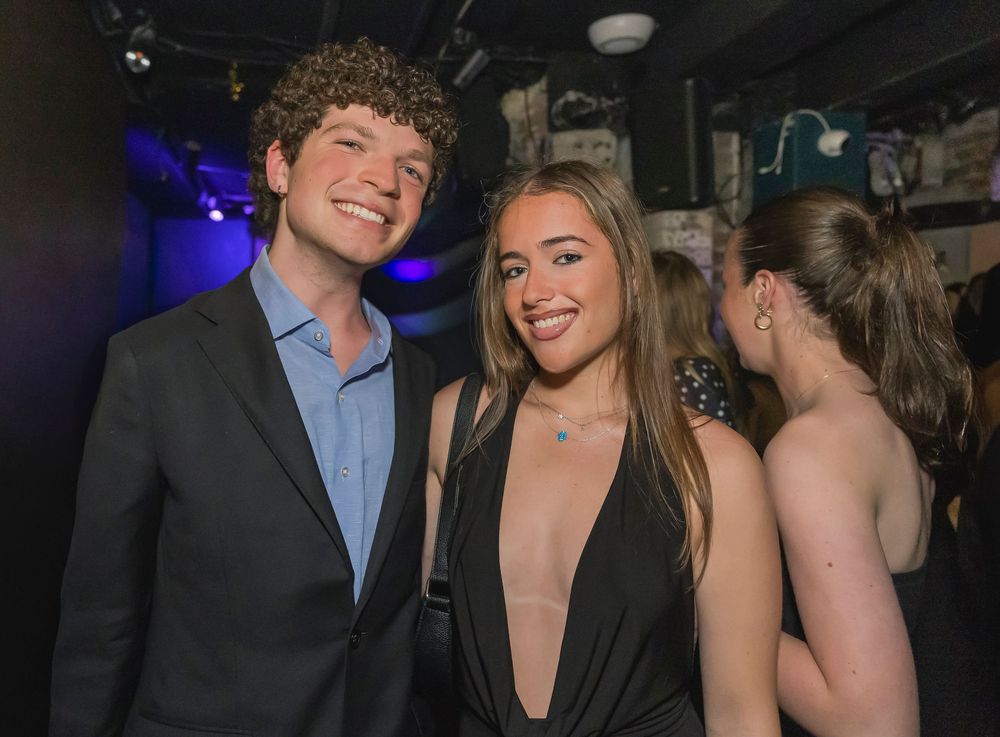 A group of young people enjoying themselves at a nightclub or social gathering with dim lighting and blue accents.