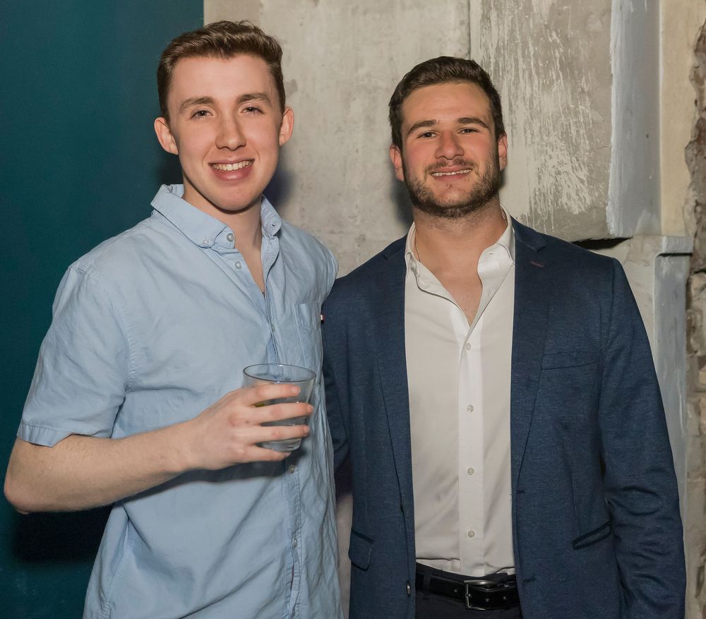 Two people in business attire pose together in a series of candid photo booth style shots against a gray background.