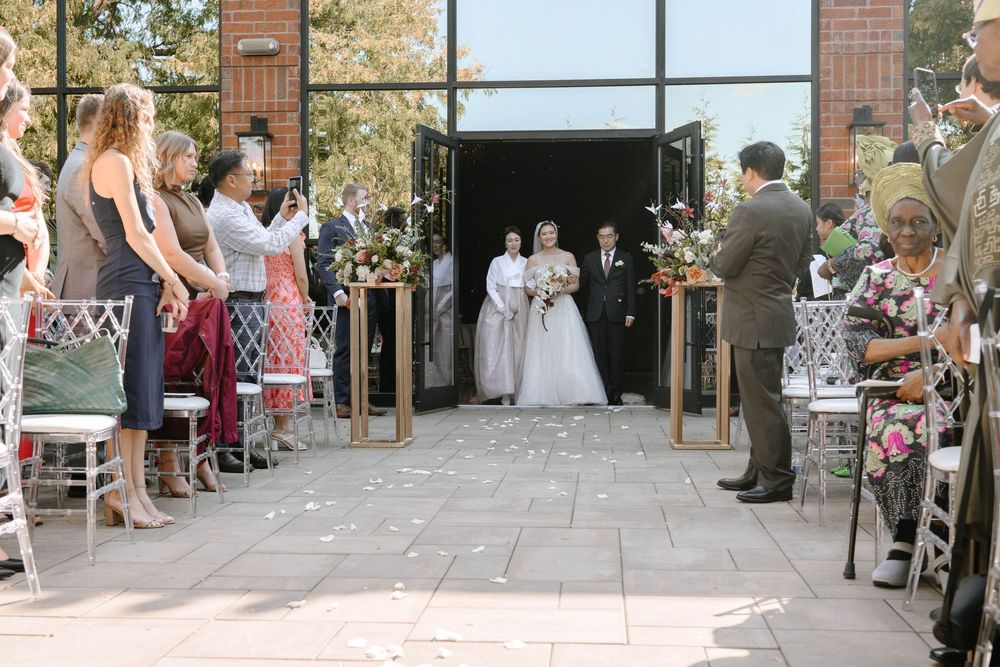 Outdoor wedding reception space with brick walls and large windows overlooking a paved patio area.