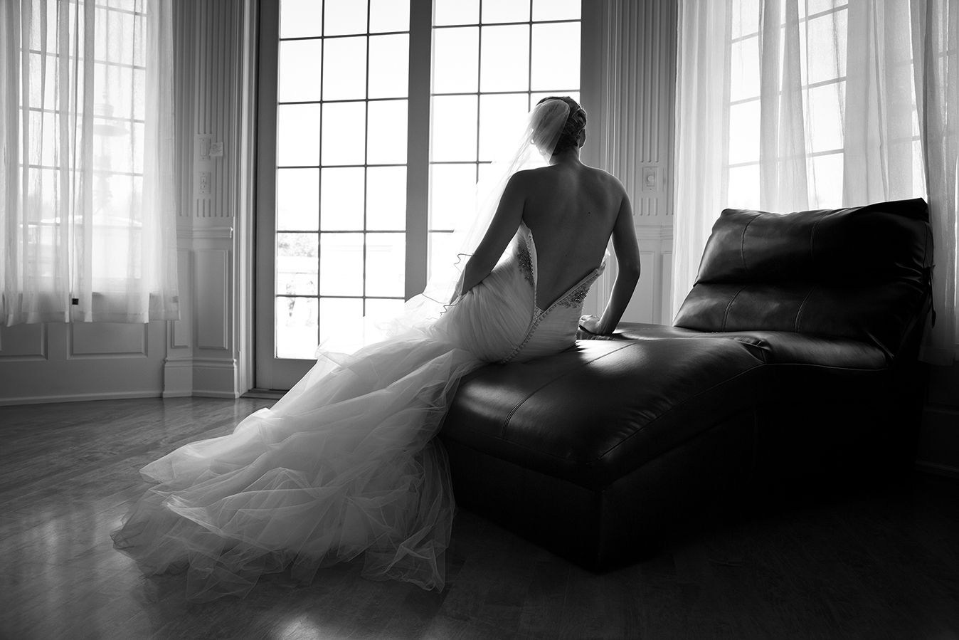 Dramatic black and white silhouette of a person in flowing gown sitting by bright window in elegant room. (Mendon New York)