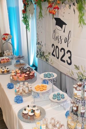 Dessert table decorated with blue accents and greenery featuring cupcakes and treats.