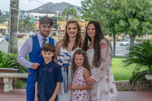 Family gathering outdoors with palm trees and mountains in the background.