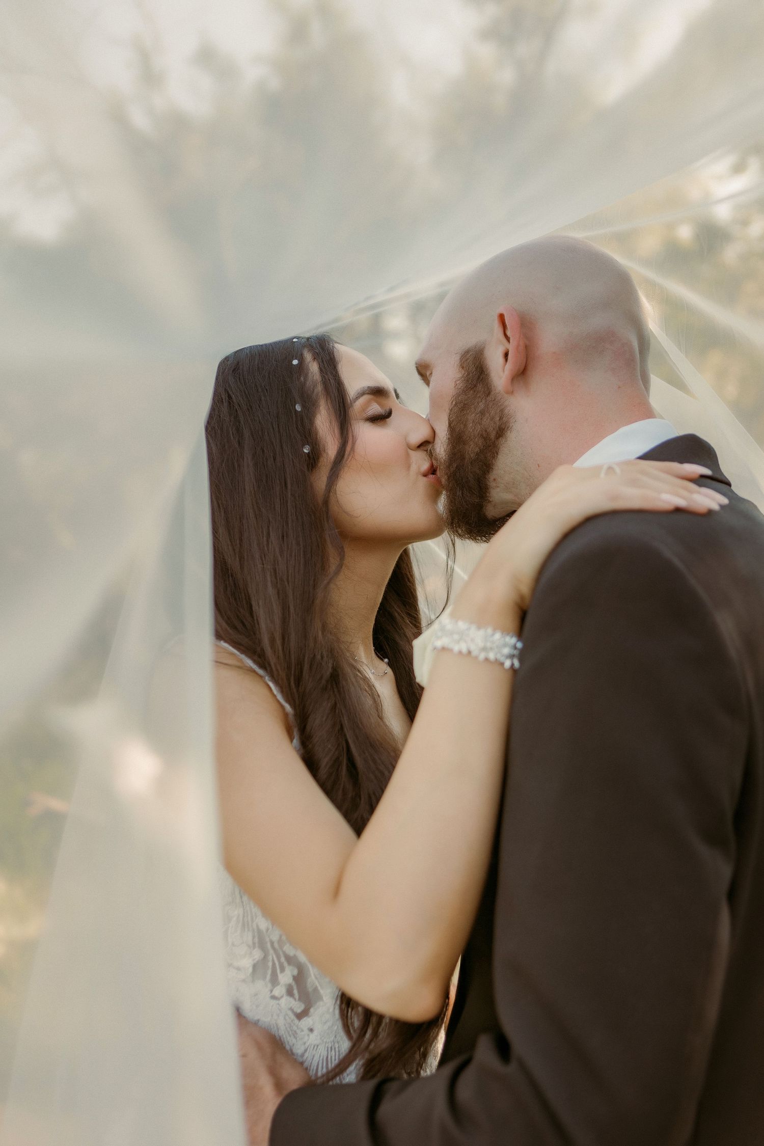 Intimate wedding moment captured in soft natural light outdoors.