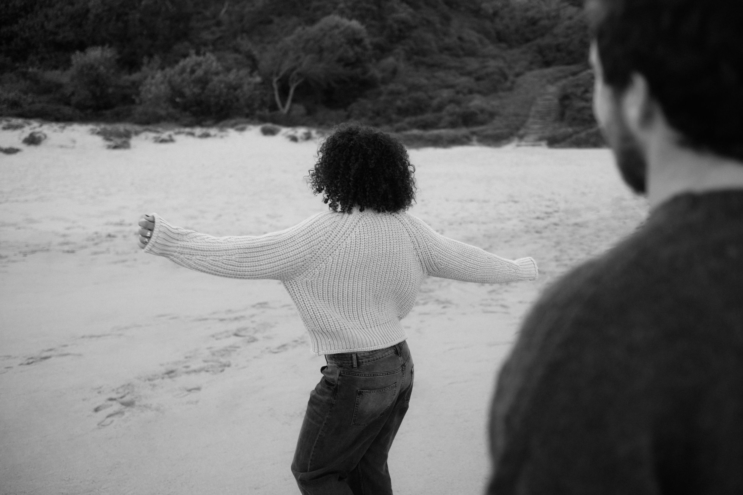 A woman dancing on a beach in front of her partner.