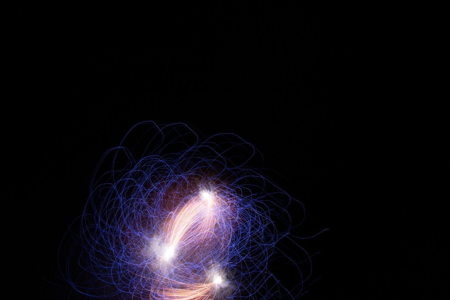 Abstract blue and pink light trails swirling in darkness.