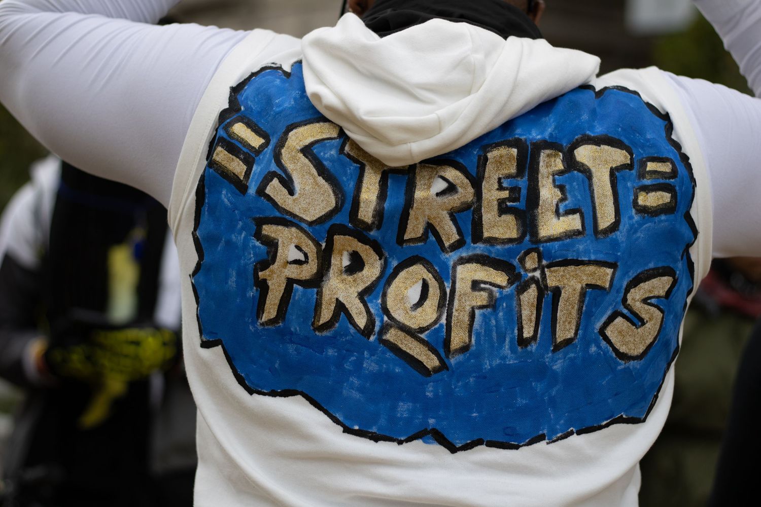White hoodie with blue street profits text design shown from behind.