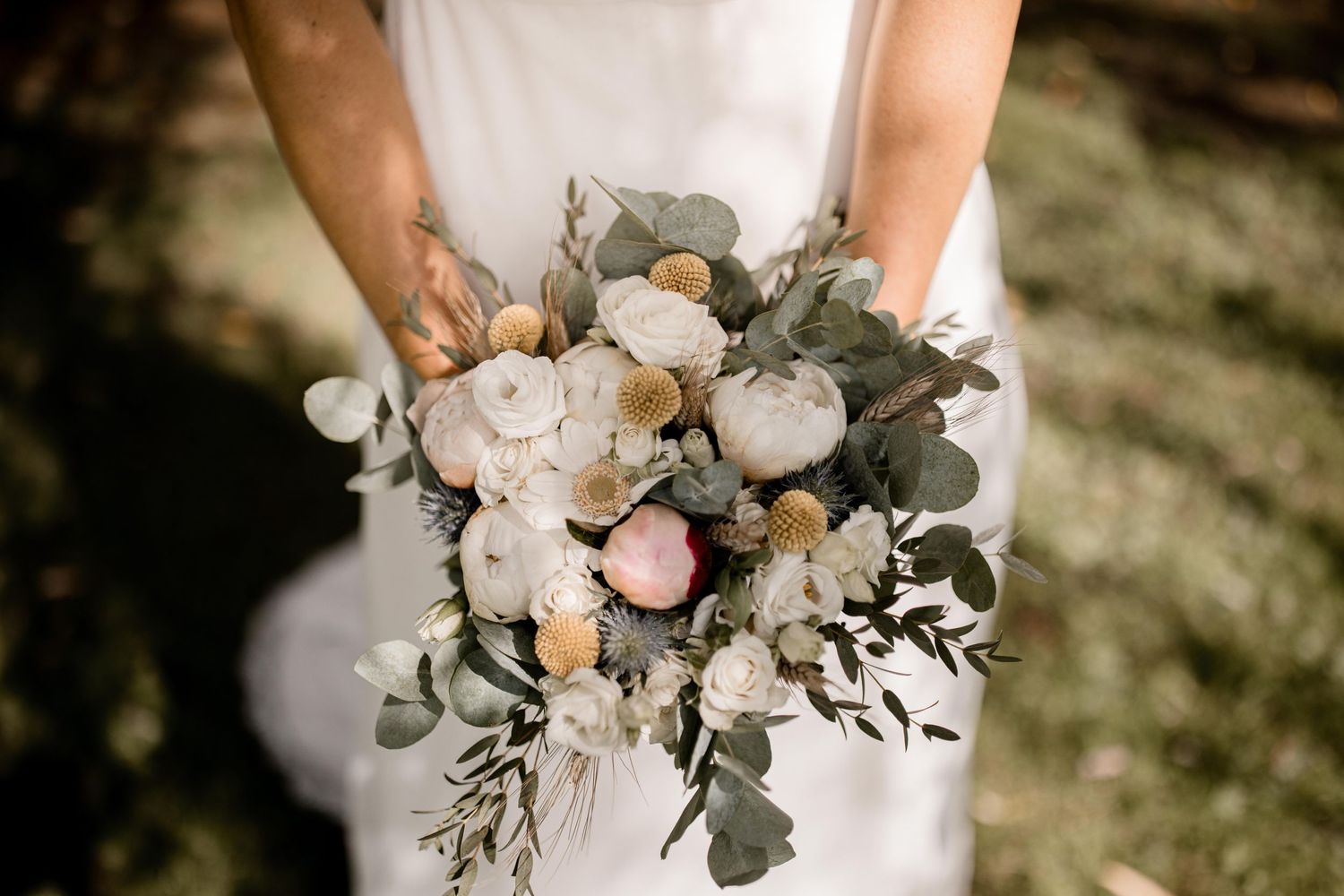 Un élégant bouquet de mariée comprend des roses blanches, des pivoines et des feuilles d'eucalyptus dans un style de jardin romantique.