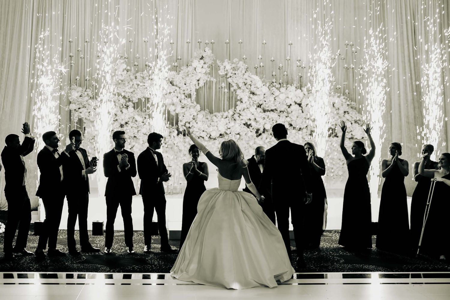 Bride in white strapless wedding gown holds bouquet of white roses while seated.