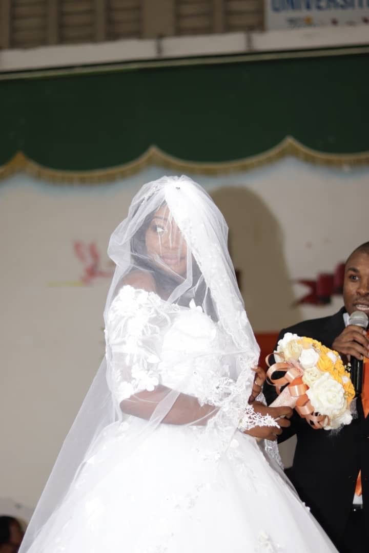 A bride in an elegant white wedding dress holding a bouquet of flowers.