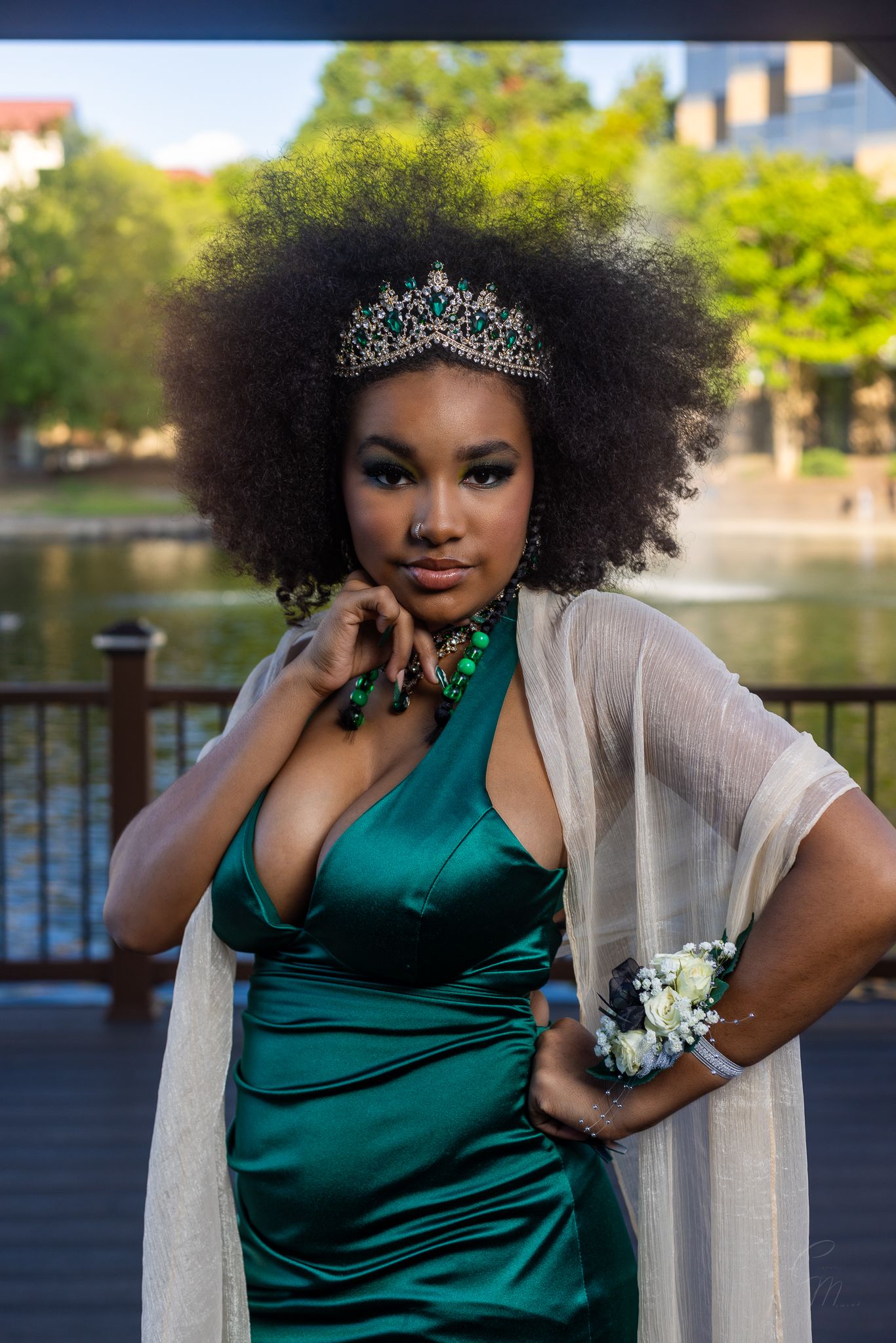 Elegant outdoor portrait in emerald satin gown with tiara and sheer wrap.