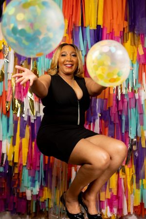 Joyful celebratory photo with colorful streamers and floating balloons.