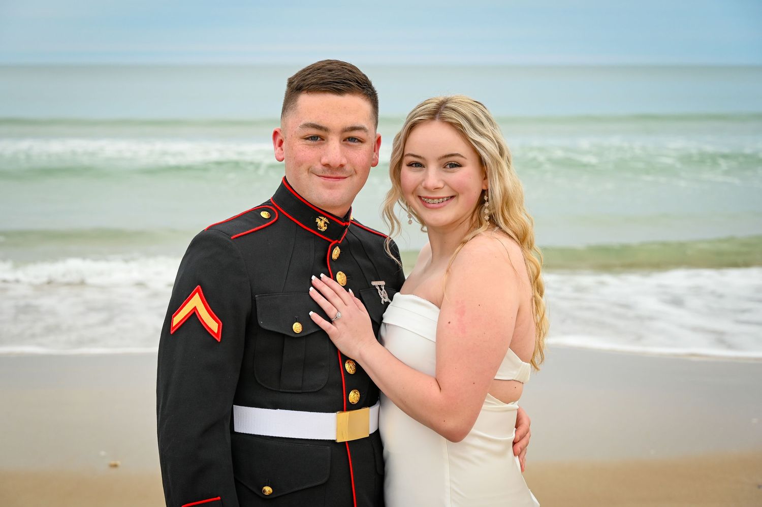 A couple poses together on a beach during a military wedding photoshoot.