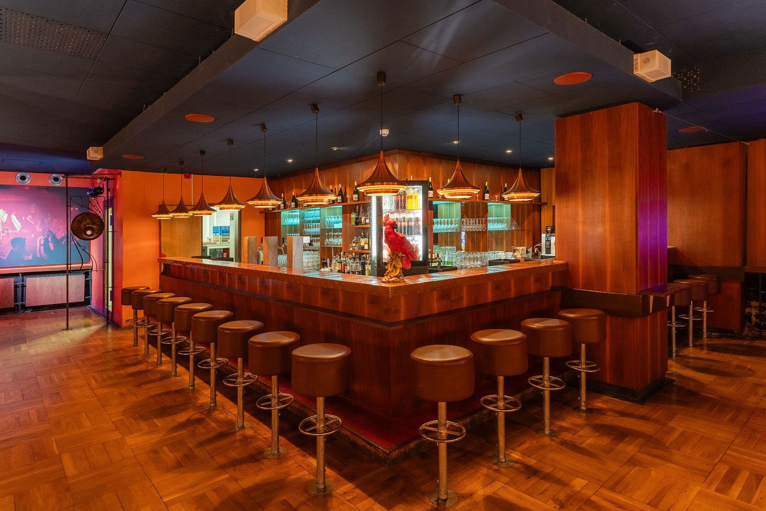 Panoramic view of dimly lit restaurant interior with orange lighting and booth seating. Parkhotel | Dresden