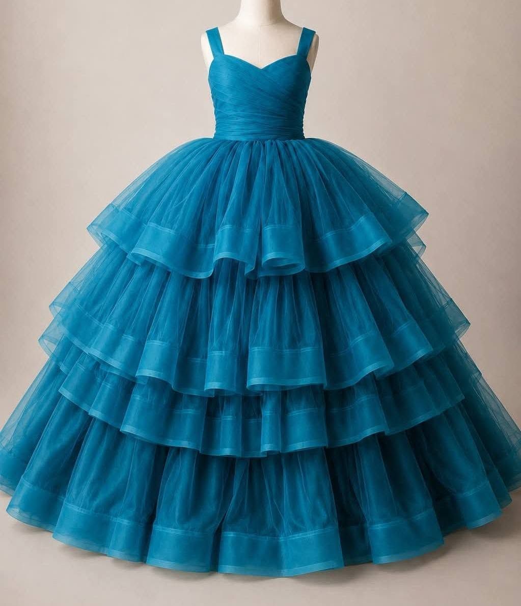 Elegant teal ball gown swirls dramatically against a misty blue-gray background in a dreamy portrait session.