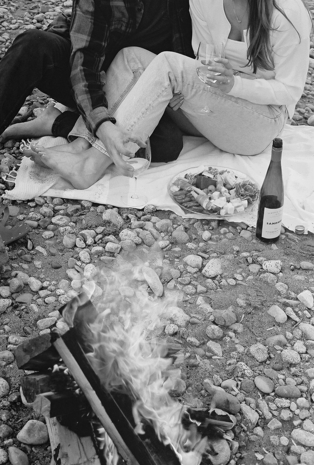 Campfire smoke rising from rocky beach picnic scene in black and white.