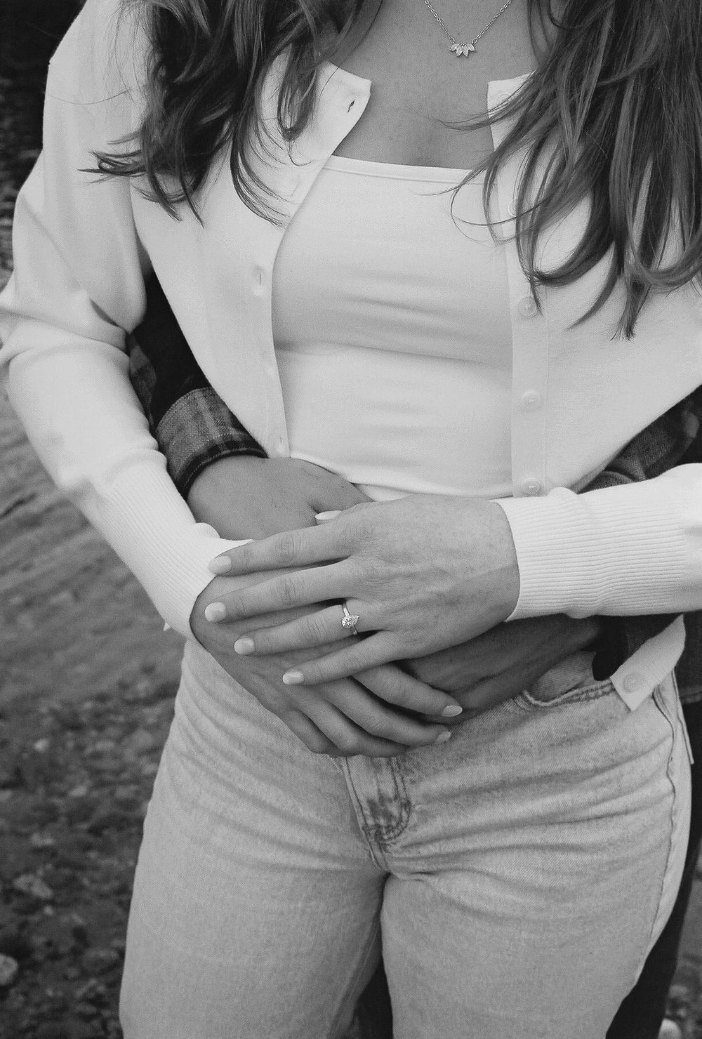 Close-up shot showing hands embracing around a waist in jeans and white top.