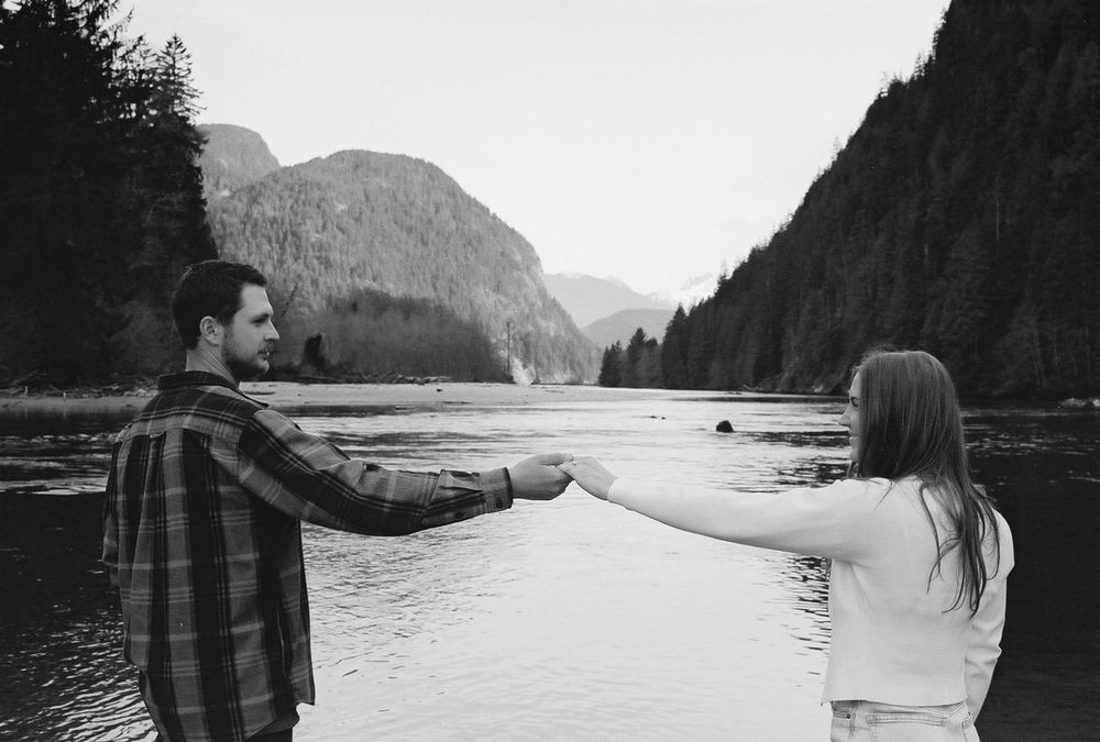 Wide panoramic view of a scenic mountain lake with couple in silhouette.